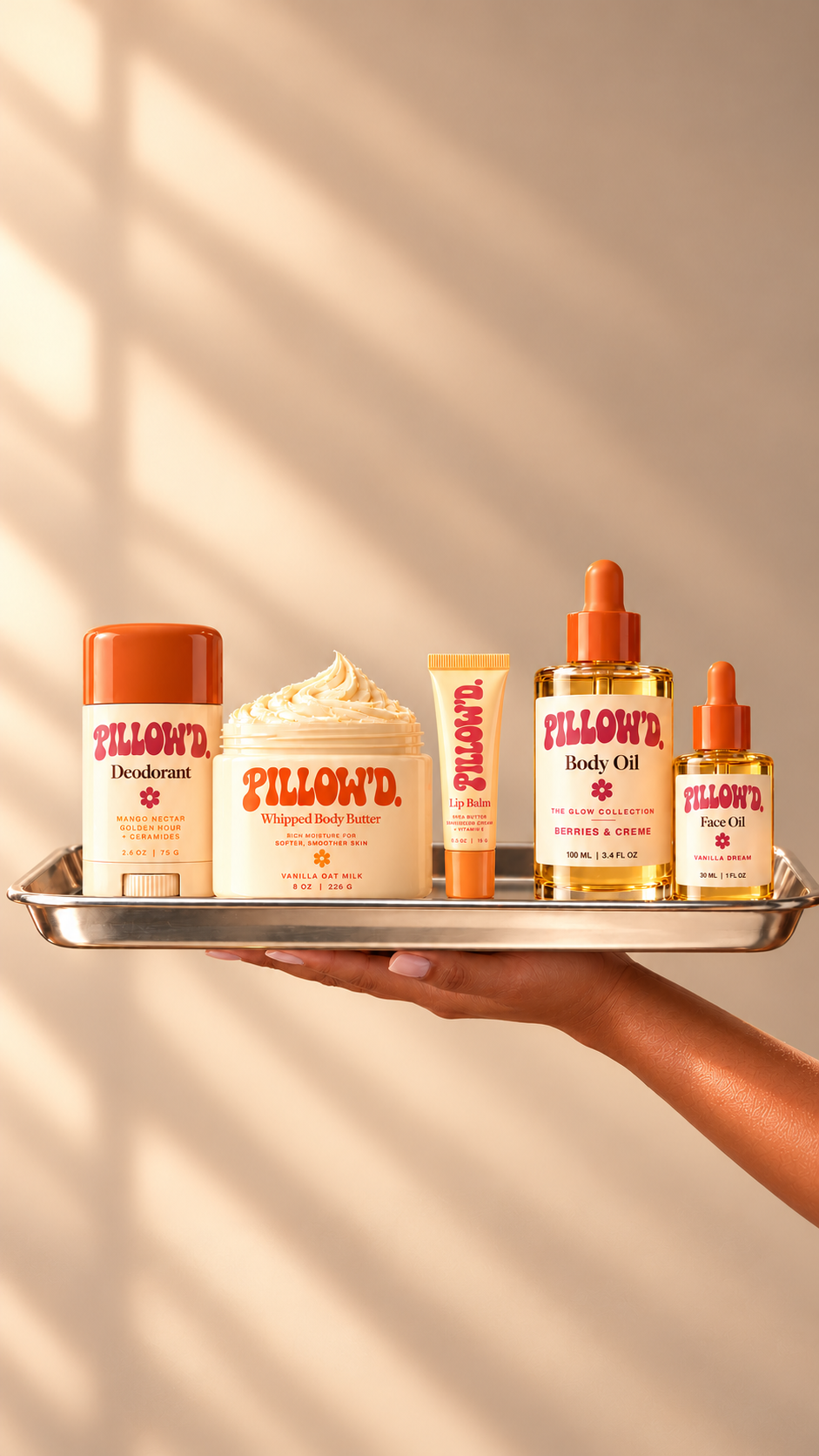 Pillow’d deodorant, whipped body butter, lip balm, body oil and face oil on a silver tray in golden-hour light